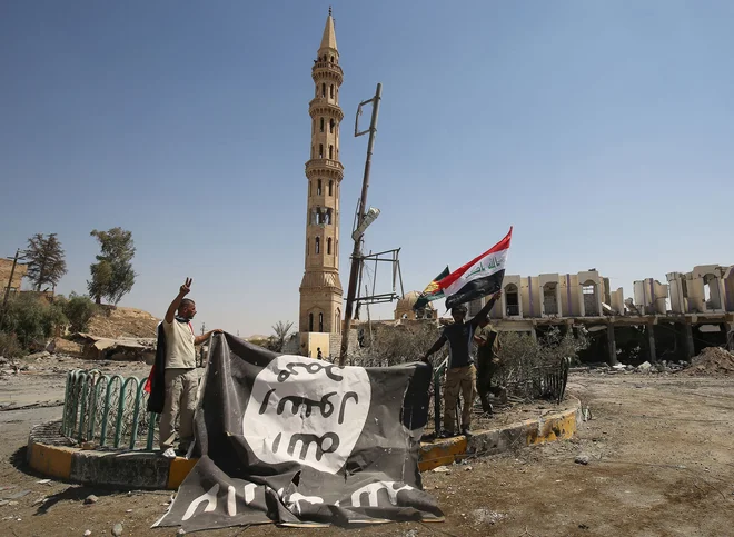 Moška ob zastavi, ki jo je med osvobajanjem območja Tal Afar v Siriji leta 2017 zapustila Islamska država. FOTO:&nbsp;Ahmad Al-rubaye/AFP