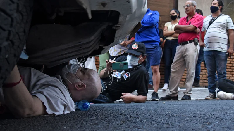 Fotografija: Nekdanji paragvajski opozicijski senator Paraguay Cubas se je priklenil na policijski avto med protestom v Asuncionu. Cubas je obsodil uporabo policijskega avtomobila za domnevne osebne namene. FOTO: Daniel Duarte/Afp