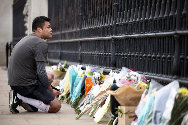 Londončani ob ograjo Buckinghamske palače polagajo cvetje v spomin na pokojnega princa. FOTO: Henry Nicholls/Reuters