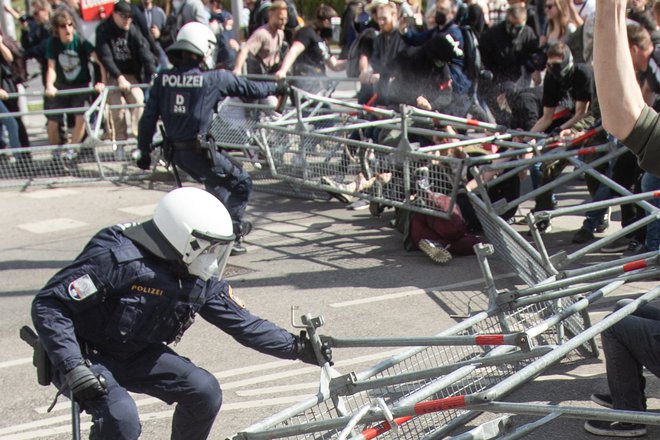 Protestniki so se ulegli na tla, policisti se varujejo z ograjo. FOTO: Alex Halada/AFP