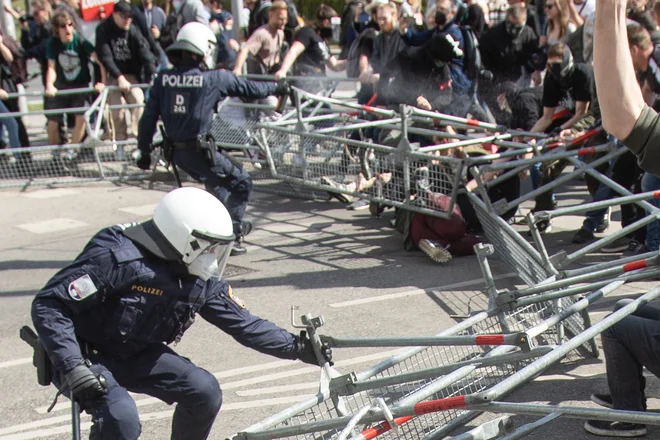 Protestniki so se ulegli na tla, policisti se varujejo z ograjo. FOTO: Alex Halada/AFP