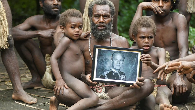 Fotografija: Poglavar vasi Yakel Albi in člani njegove družine, ki živijo na oddaljeni otoški državi Vanuatu v južnem Tihem oceanu, drži portret britanskega princa Filipa, vojvode Edinburškega, ki so ga častili kot živega boga. 99-letni Princ Filip, soprog kraljice Elizabete II. je v petek umrl. Poročena sta bila več kot 73 let, imela sta štiri otroke, deset vnukov in devet pravnukov. FOTO: Dan Mcgarry/Afp