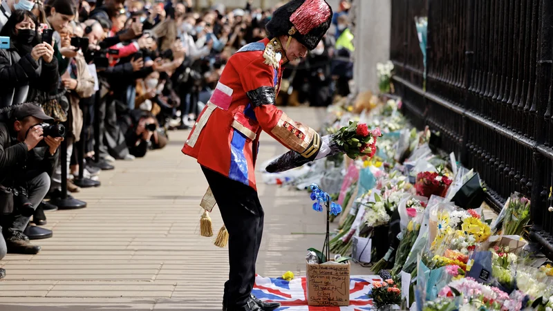 Fotografija: Oboževalec kraljeve družine je bil eden od mnogo Londončanov, ki so k ograji Buckinghamske palače prejšnji teden položili cvetje v spomin na pokojnega princa Filipa. Foto: Tolga Akmen/AFP