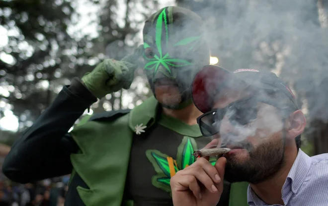 Moški kadi džoint v parku v Bogoti na neuradnem prazniku zagovornikov konoplje 20/4, na katerem se tradicionalno organizirajo marihuana marši. FOTO: Raul Arboleda/Afp