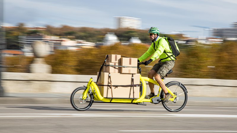 Fotografija: Dostavljač v enem od evropskih mest prevaža pošiljko na tovornem kolesu v podaljšani izvedbi. Sliši se zanimivo, a kolesarske steze pri nas za to niso primerne.
FOTO: Shutterstock