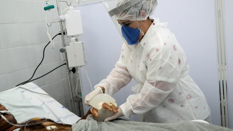 Fotografija: Medicinska sestra Vanessa Formenton nezavestnemu bolniku namešča male roke ljubezni. FOTO: Amanda Perobelli/Reuters