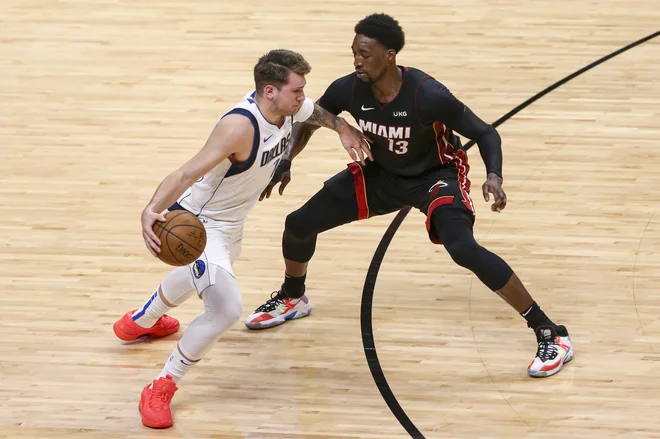 Luka Dončić in Miamijev center Bam Adebayo v dvoboju. FOTO: Sam Navarro/Usa Today Sports