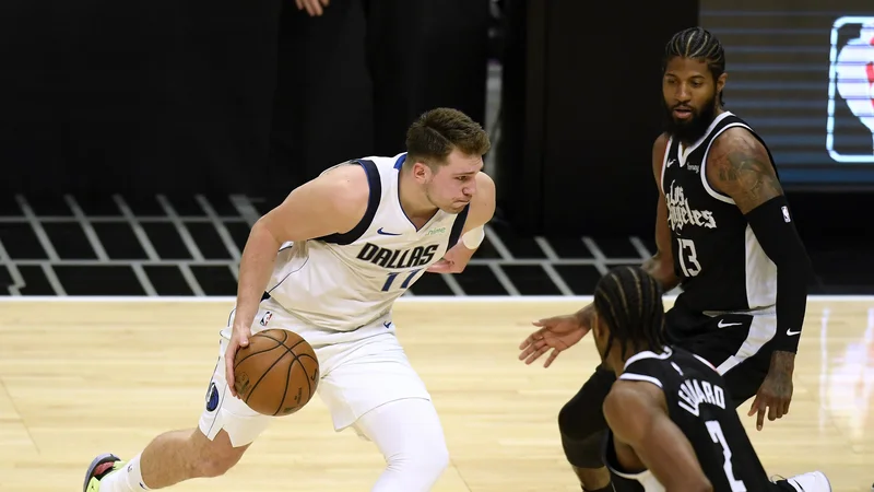Fotografija: Luka Dončić je dobro vedel, kaj mora narediti, ko sta ga pokrivala tako Paul George (13) kot Kawhi Leonard (2). FOTO Harry How/AFP