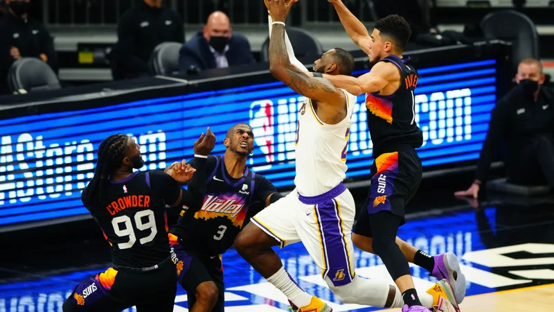 Fotografija: LeBron James je ob najboljšemu strelcu Phoenixa Devinu Bookerju položil žogo v koš, a končnico so branilci naslova LA Lakers začeli z zaostankom z 0:1 v zmagah. FOTO: Mark J. Rebilas/Usa Today Sports