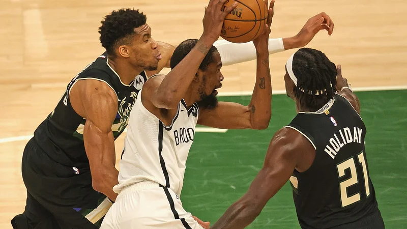 Fotografija: Kevin Durant (z žogo) prodira ob Giannisu Antetokounmpu (levo) in Jrueju Holidayu na šesti tekmi v Milwaukeeju. FOTO: Jonathan Daniel/AFP