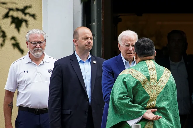Ameriški predsednik pozdravlja duhovnika po končani maši pred &shy;katoliško cerkvijo v Wilmingtonu. FOTO: Alexander Drago/Reuters