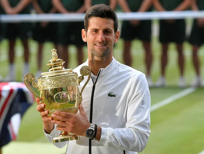 Novak Đoković je leta 2019 takole poziral s pokalom za najboljšega v Wimbledonu. FOTO: Toby Melville/Reuters