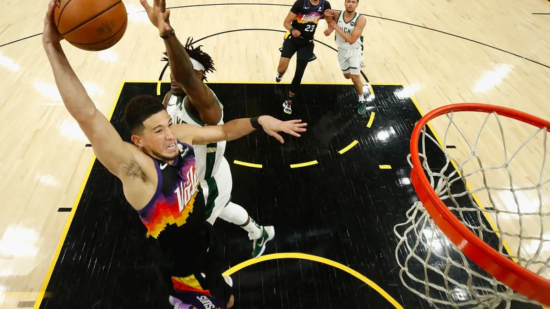 Fotografija: Devin Booker (z žogo) se pripravlja na zabijanje ob Jrueju Holidayu. FOTO: Christian Petersen/AFP