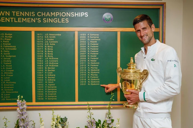 Novak Đoković je s pokalom v rokah ponosno pokazal na svoje ime na tabli z zmagovalci. FOTO: Thomas Lovelock/AFP