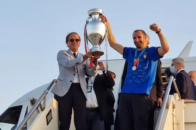 Selektor Italije Roberto Mancini in kapetan Giorgio Chiellini sta varno pripeljala lovoriko za najboljšega v Evropi v domovino, kjer so nogometaši dvignili na noge Apenine. FOTO: AFP
