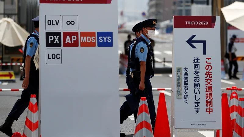 Fotografija: Deset dni pred začetkom iger policisti nadzirajo vhod v olimpijsko vas. FOTO: Issei Kato/Reuters