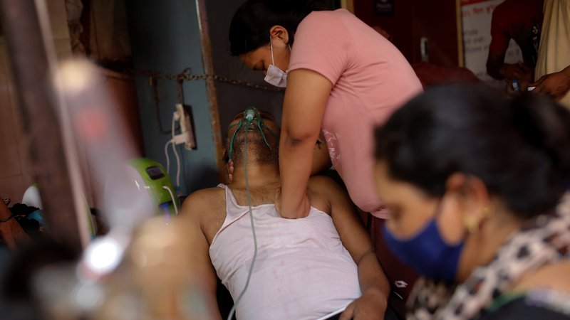 Fotografija: V indijskem mestu Ghaziabad Manisha Bashu masira prsi svojega očeta, ki ima težave z dihanjem, potem ko je izgubil zavest kljub dodatnem kisiku. FOTO: Adnan Abidi/Reuters
 