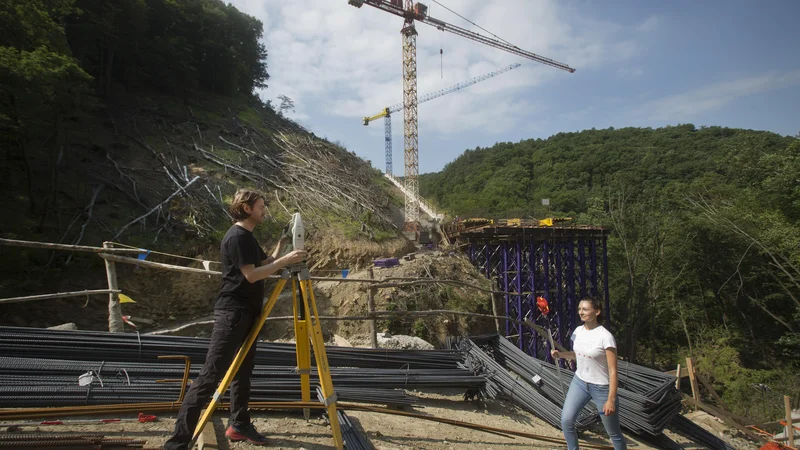 Fotografija: Geodeta Gregor Repar in Nina Stajnko iz podjetja Garnol s tahometrom merita in računata koordinate za nastajajoči zadnji opornik mostu čez Glinščico. Vsak meter mostu tehta 65 ton, zato je natančnost nujna. FOTO: Jure Eržen/Delo