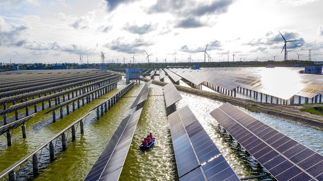 Električarji s čolni preverjajo solarne panele na fotovoltaični elektrarni, zgrajeni na ribniku v kitajskem Haianu. FOTO: AFP