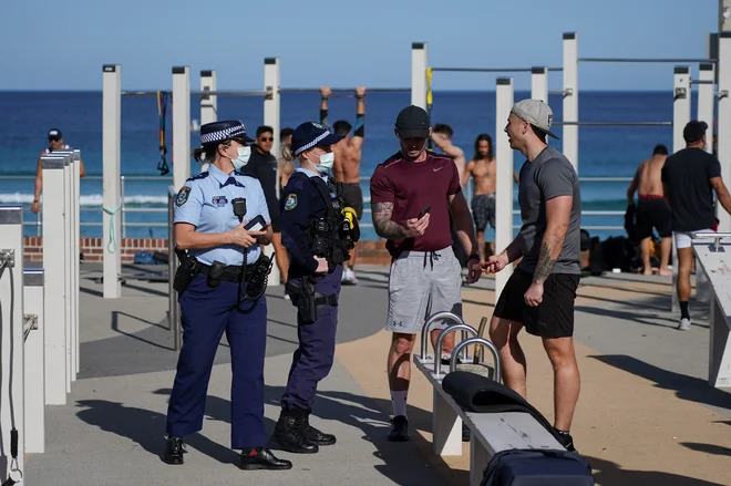 Policija preverja vse, ki se gibljejo zunaj, med drugim so patruljo postavili tudi pred eno od večstanovanjskih stavb v Sydneyju, kjer je s covidom okuženih šest prebivalcev. Nihče od tam živečih ne sme zapustiti stavbe 14 dni, hrano in druge potrebščine pa jim dostavljajo. FOTO: Loren Elliott/Reuters