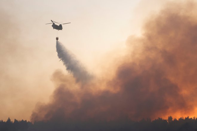 Z ognjem se bori okoli 500 gasilcev, pomaga jim pet helikopterjev in na desetine letal. FOTO: Giorgos Moutafis/Reuters