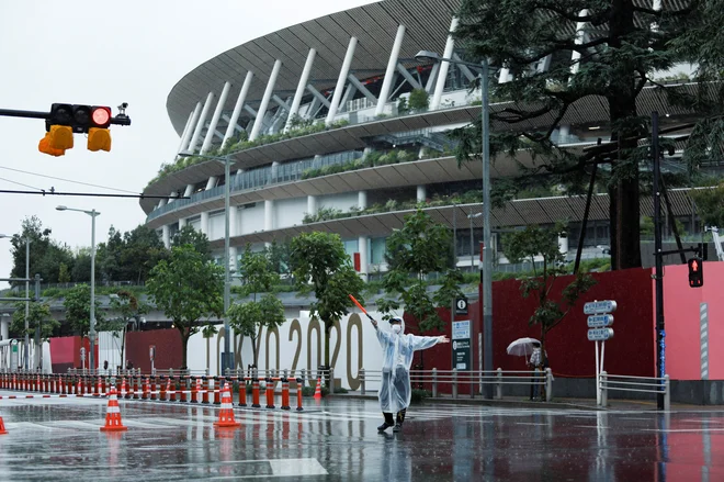 Policist ob olimpijskem stadionu, ki ga je na zadnji dan iger &raquo;obiskal&laquo; tudi tajfun. FOTO: Androniki Christodoulou/Reuters
