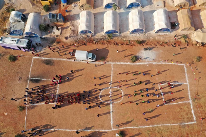 Na severozahodu sirske pokrajine Idlib so na igrišču kampa za razseljene Sirce organizirali taboriščne olimpijske igre za tamkajšnje mlade športnike. 120 fantov iz 12 različnih kampov je doživelo svojo različico olimpijskih iger. V Idlibu živi skoraj tri milijone ljudi, dve tretjini jih je bilo med desetletnim spopadom razseljenih iz drugih delov države. Večina tistih, ki so izgubili domove, živi v kampih po vsej regiji, kjer prevladujejo džihadisti. FOTO: Omar Haj Kadour/Afp<br />
