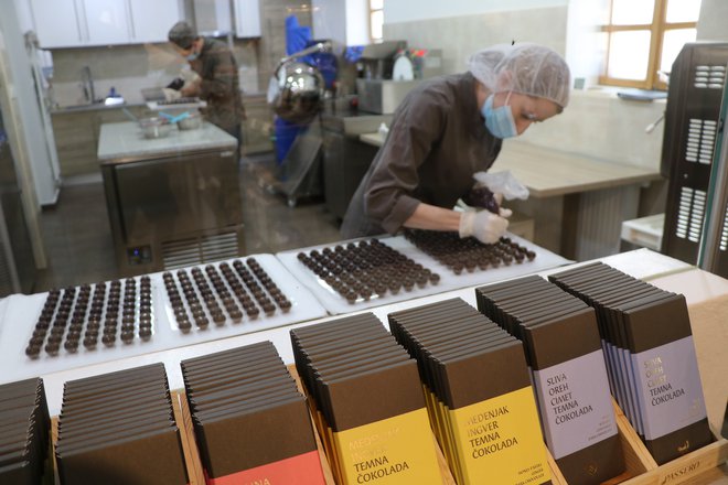 Radovedneži lahko iz prodajalne skozi steklo pokukajo v proizvodnjo čokolade in pralinejev. FOTO: Jože Pojbič/Delo