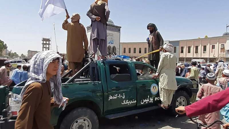 Fotografija: Talibski borci na poškodovanem vozilu policije v mestu Kandahar.
FOTI: AFP