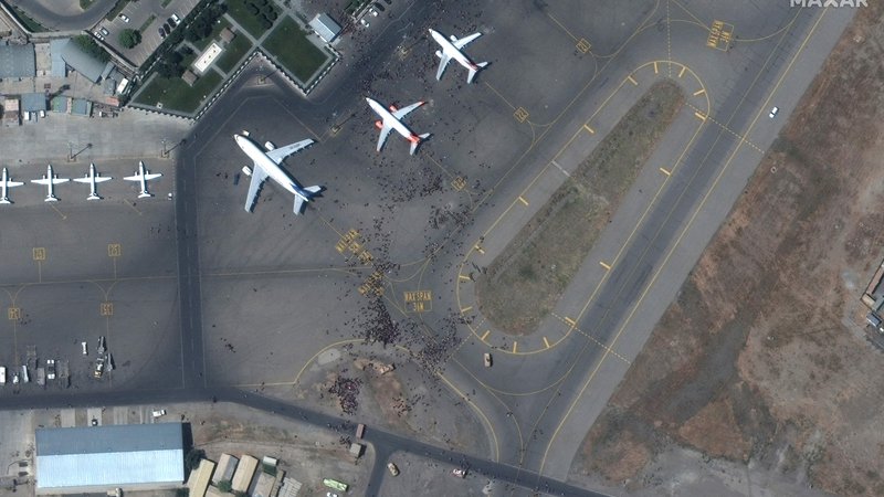 Fotografija: Z letališča so ves dan prihajali dramatični posnetki z množico ljudi na prostoru, kjer so parkirana letala za izkrcanje in vkrcanje potnikov. FOTO: Maxar Technologies/AFP