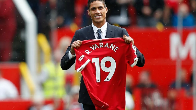 Fotografija: Varane je z novim dresom v rokah pozdravil navijače pred zadnjo ligaško tekmo na Old Traffordu. Foto Adrian Dennis/Afp