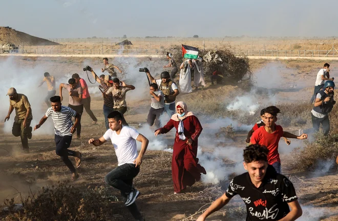 Palestinski demonstranti in novinarji so bežali pred solzivcem, ki so ga izraelske varnostne sile uporabljale med protestom vzdolž mejne ograje, vzhodno od Khana Yunisa na jugu Gaze. FOTO: Mahmud Hams/Afp
