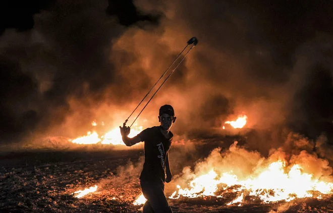 Palestinci se s kamenjanjem in fračami spopadajo z izraelsko vojsko na demonstracijah ob meji med Gazo in Izraelom vzhodno od Gaze. FOTO: Mahmud Hams/Afp<br />
