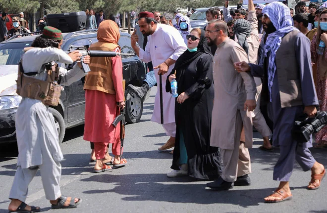 Pripadnik talibanskih sil puško usmerja proti afganistanskim protestnikom, ki na demonstracijah proti Pakistanu vzklikajo slogane v bližini pakistanskega veleposlaništva v Kabulu. FOTO: Stringer/Reuters<br />
