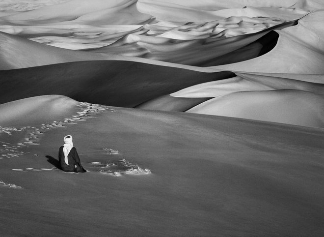 Nekatere Salgadove fotografije niso brutalno šokantne, ampak polne transcendentalne poetike. Na eni vidimo človeka s turbanom – sedi v puščavi v Alžiriji in gleda v neskončne peščene sipine (2009). FOTO: Sebastião Salgado