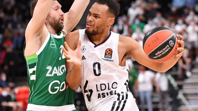 Fotografija: Elie Okobo (z žogo) med prodorom ob Janisu Strelnieksu na obračunu Asvela in Žalgirisa v lyonem Villeurbannu. FOTO: Philippe Desmazes/AFP