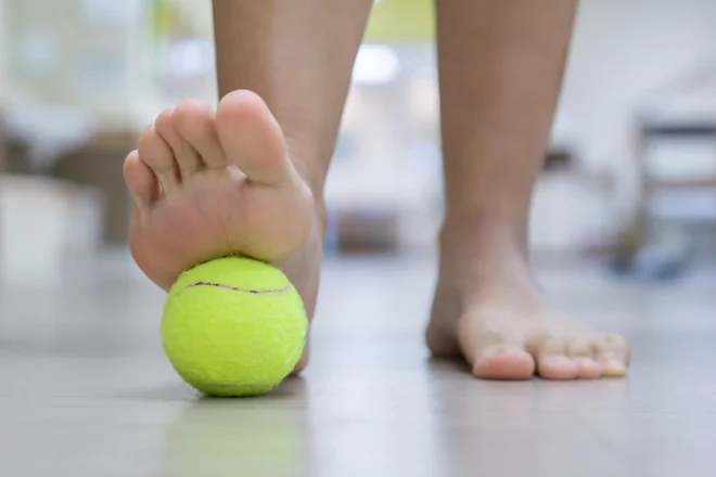 Uporaba teniških žogic pod nogami lahko takoj in učinkovito raztegne tetive in mečne mišice in izboljša prožnost v spodnjem delu hrbta in tako lajša bolečine. FOTO: Shutterstock