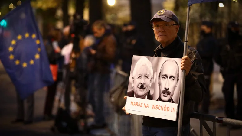 Fotografija: Protestnik pred stavbo poljskega ustavnega sodišča s portretoma poljskega pravosodnega ministra Jarosława Kaczyńskega in ruskega predsednika Vladimirja Putina v vlogi diktatorjev. FOTO: Jaap Arriens/AFP