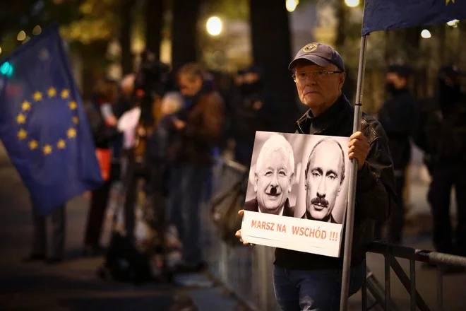 Protestnik pred stavbo poljskega ustavnega sodišča s portretoma poljskega pravosodnega ministra Jarosława Kaczyńskega in ruskega predsednika Vladimirja Putina v vlogi diktatorjev. FOTO: Jaap Arriens/AFP