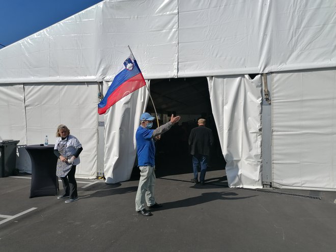 Udeleženec zbora SDS je v šotor zakorakal s slovensko zastavo. FOTO: Nataša Čepar/Delo