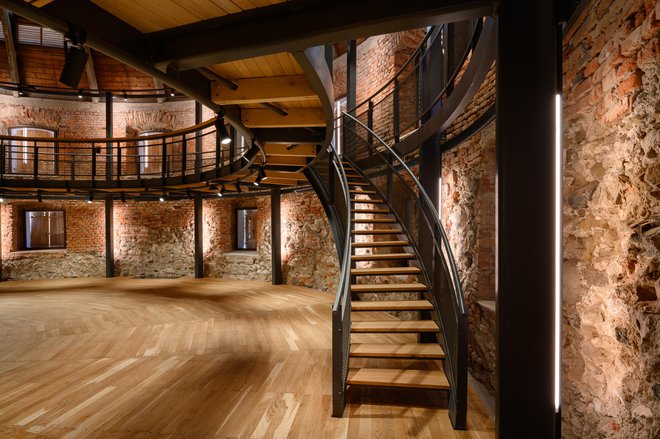 Stopnice, ki povezujejo etaži, vodijo v zunanji atrij, k točilnemu pultu letnega lutkovnega avditorija.
