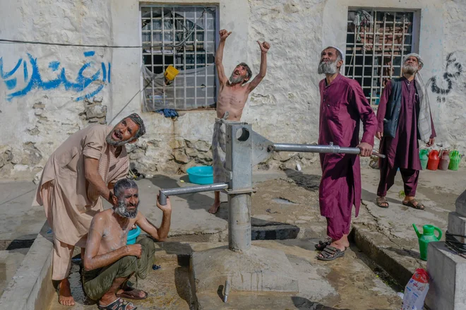 TOPSHOT - Drug addicted prisoners look at a helicopter flying over while washing at a yard in Kandahar Central prison, in Kandahar on October 28, 2021. (Photo by BULENT KILIC/AFP) Foto Bulent Kilic Afp