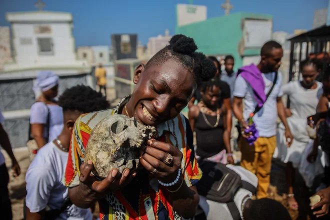 Ljudje molijo med slovesnostjo v čast haitijskega vudu duha barona Samedija in Gedeja na pokopališču v Port-au-Princeu. Mnogi verjamejo, da je praznovanje vudu duhov Fete Gede enakovredno rimskokatoliškemu prazniku dneva mrtvih. FOTO: Richard Pierrin/Afp