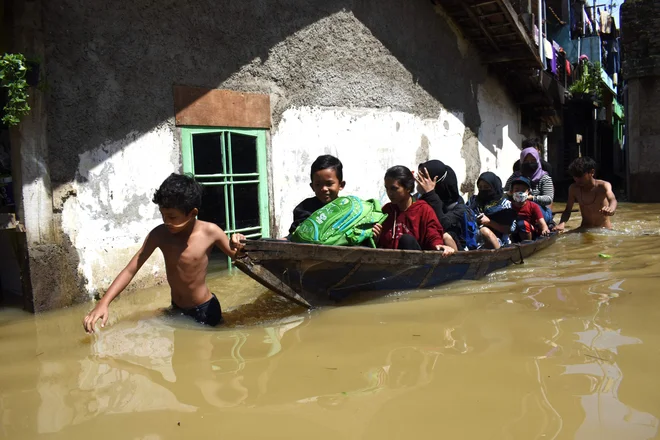 Družina se je bila primorana evakuirati iz poplavljenega doma po močnem dežju v indonezijskem mestu Bandung. FOTO: Timur Matahari/AFP
