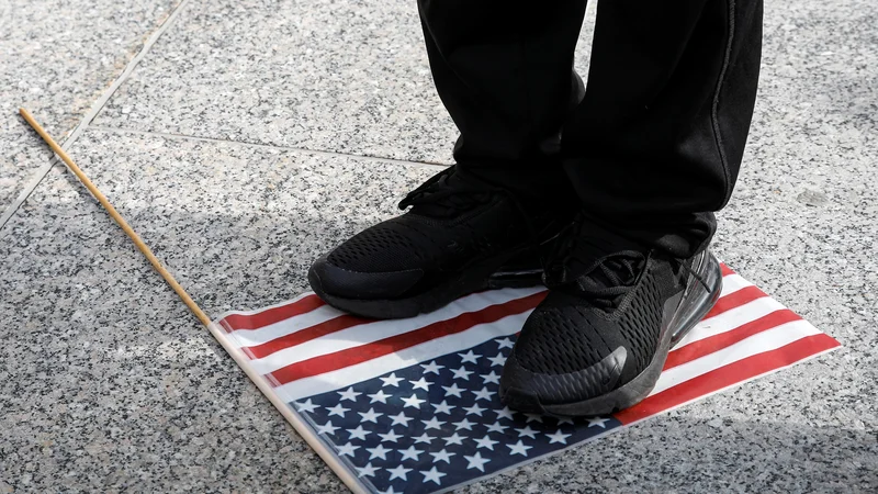Fotografija: Teptanje ameriške zastave pred sodiščem v Kenoshi med izbiranjem porote za proces proti Kylu Rittenhousu, ki je med lanskimi protersti ubil dva človeka. FOTO: Brendan Mcdermid/Reuters