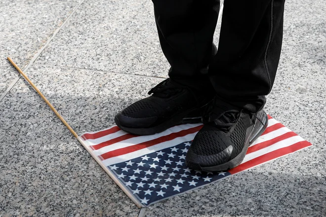 Teptanje ameriške zastave pred sodiščem v Kenoshi med izbiranjem porote za proces proti&nbsp;Kylu&nbsp;Rittenhousu, ki je med lanskimi protersti ubil dva človeka. FOTO: Brendan Mcdermid/Reuters

