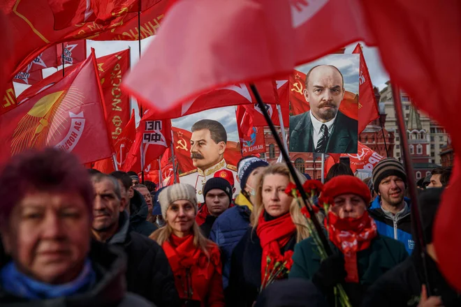 Aktivisti in podporniki ruske komunistične partije nosijo portrete ustanovitelja Sovjetske zveze Vladimirja Lenina in sovjetskega diktatorja Josefa Stalina, med polaganjem cvetja v Leninovem mavzoleju na Rdečem trgu v središču Moskve, na slovesnosti ob 104. obletnici boljševiške oz. oktobrske revolucije. FOTO: Dimitar Dilkoff/Afp

