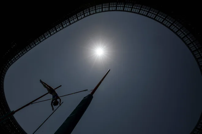 Maj 2021. Športnik tekmuje v skoku s palico na nacionalnem stadionu v Tokiu pred začetkom olimpijskih iger. FOTO: Charly Triballeau/Afp