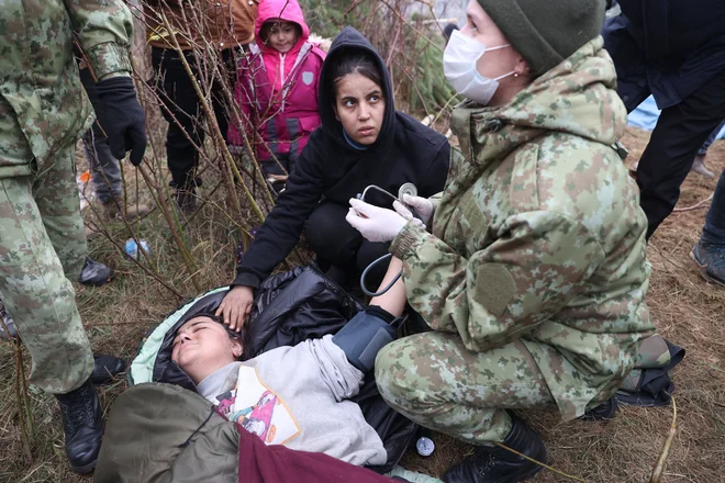 Migrant prejema zdravstveno pomoč na meji med Poljsko in Belorusijo. FOTO: Ramil Nasibulin/AFP
