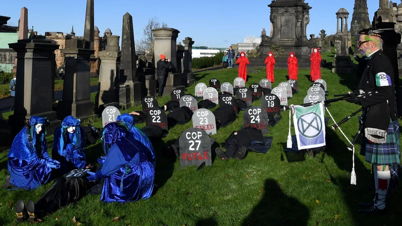 Fotografija: Aktivisti so dogovor »pokopali« s simboličnim pogrebom na pokopališču v Glasgowu. FOTO: Paul Ellis/AFP
